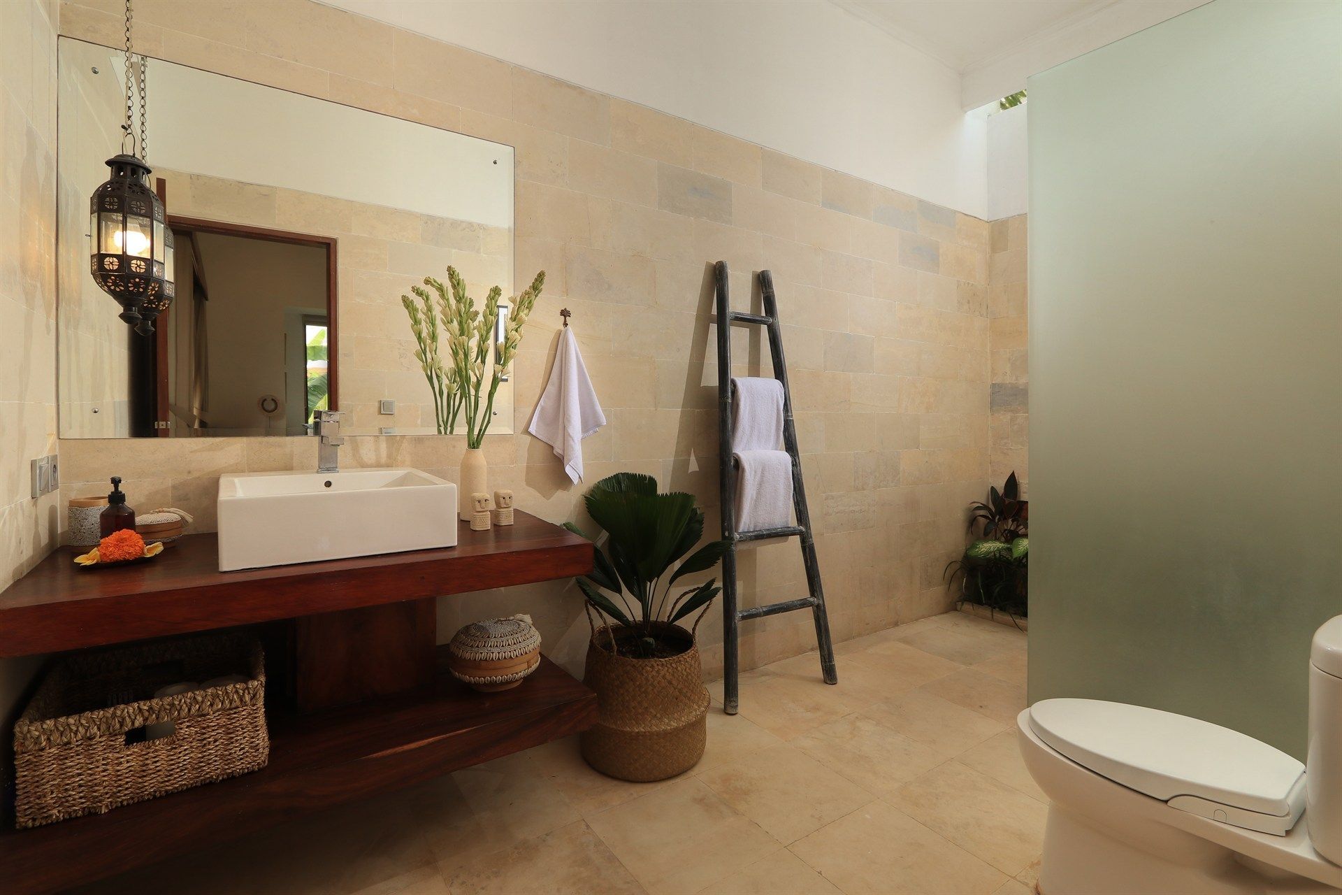 Bathroom with a vanity, toilet, and a ladder for towels. Neutral tones, natural light.