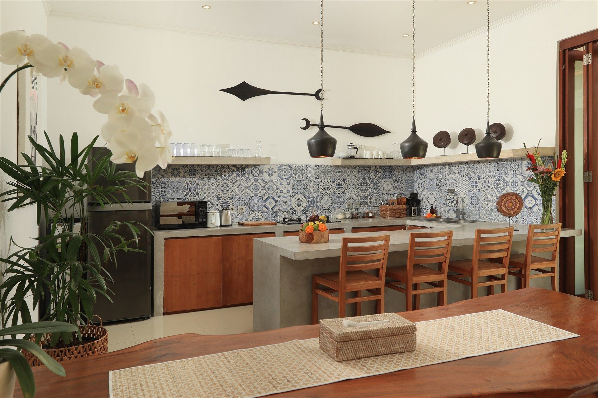 Kitchen with blue and white tile backsplash, wooden cabinets, and a dining table.
