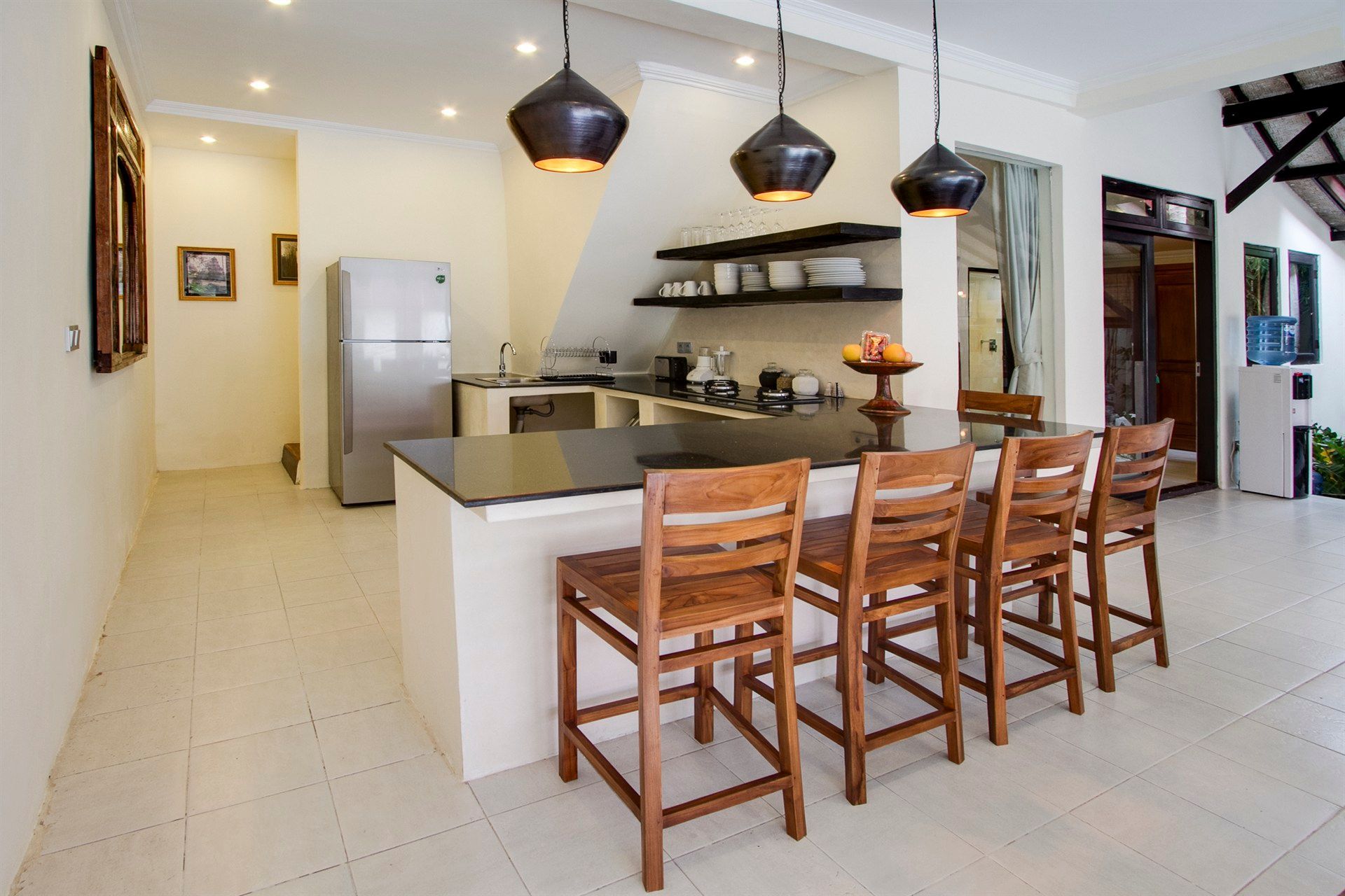 Modern kitchen with a black island, bar stools, and overhead pendant lights.