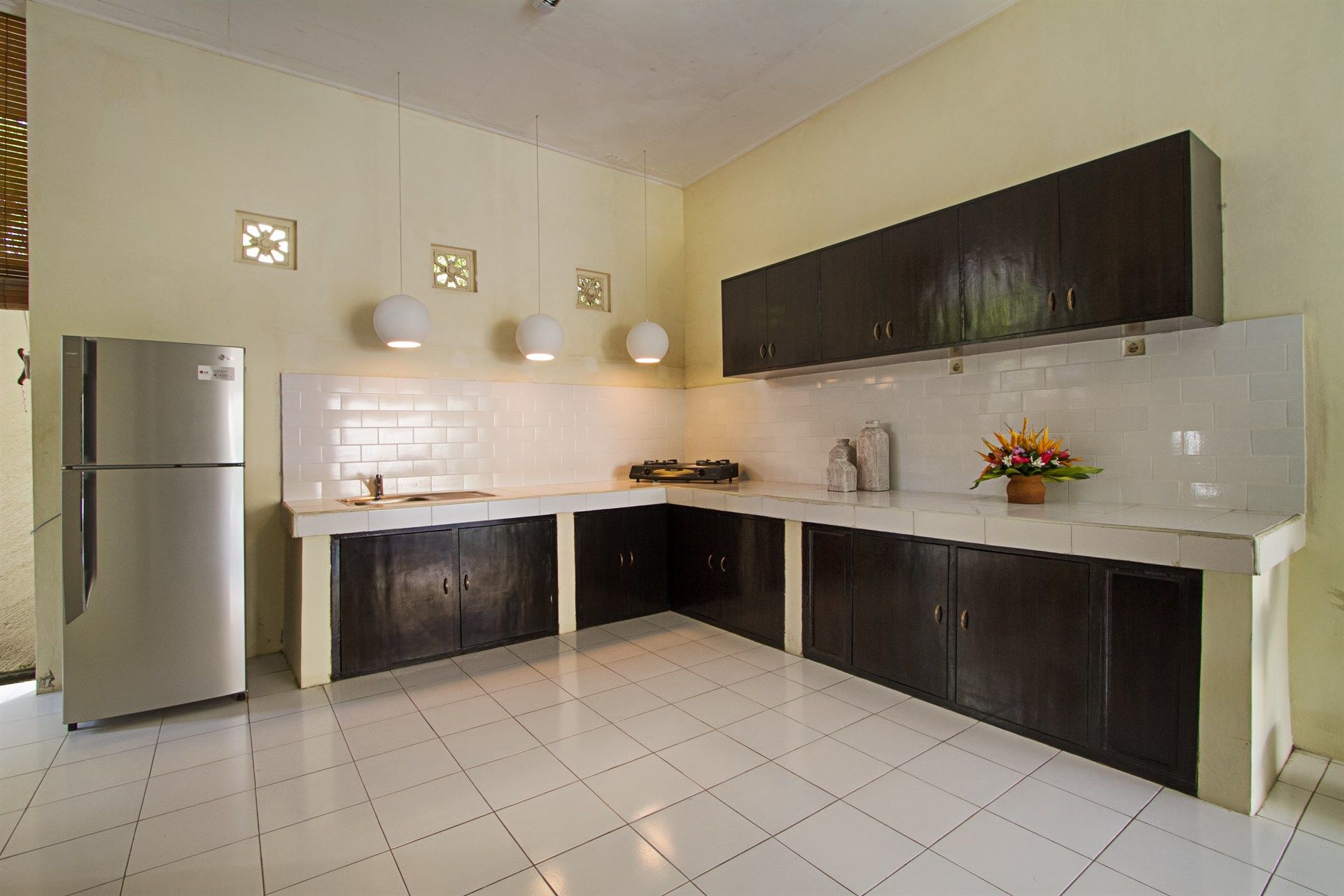 A kitchen with dark wood cabinets, white countertops, and stainless steel refrigerator.