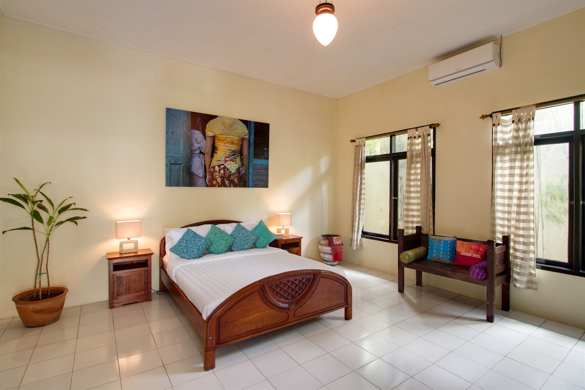 Bedroom with a wooden bed, artwork, two nightstands, and a small sitting area.