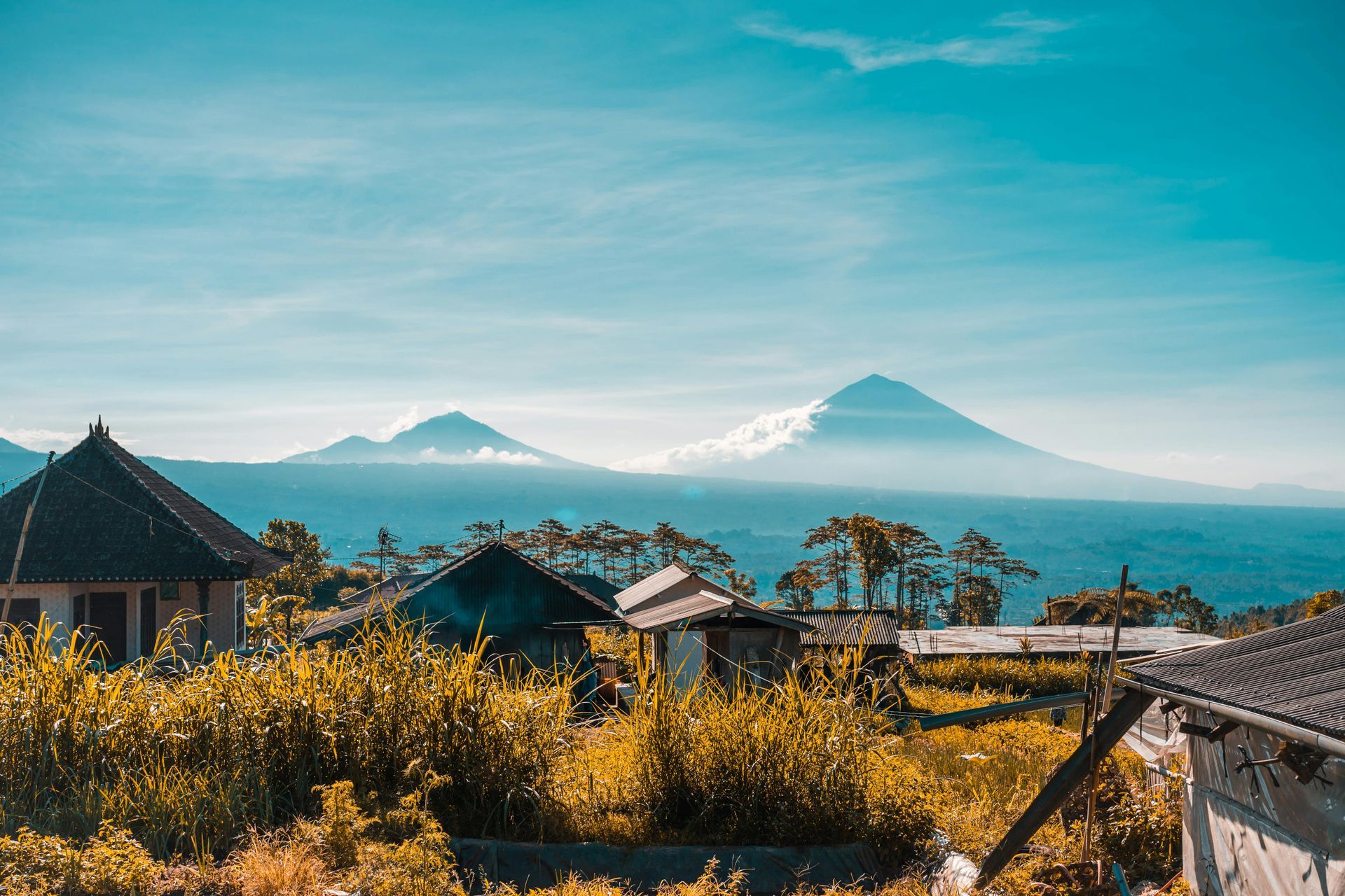 Houses in the foreground with mountain range in the distance under a blue sky.
