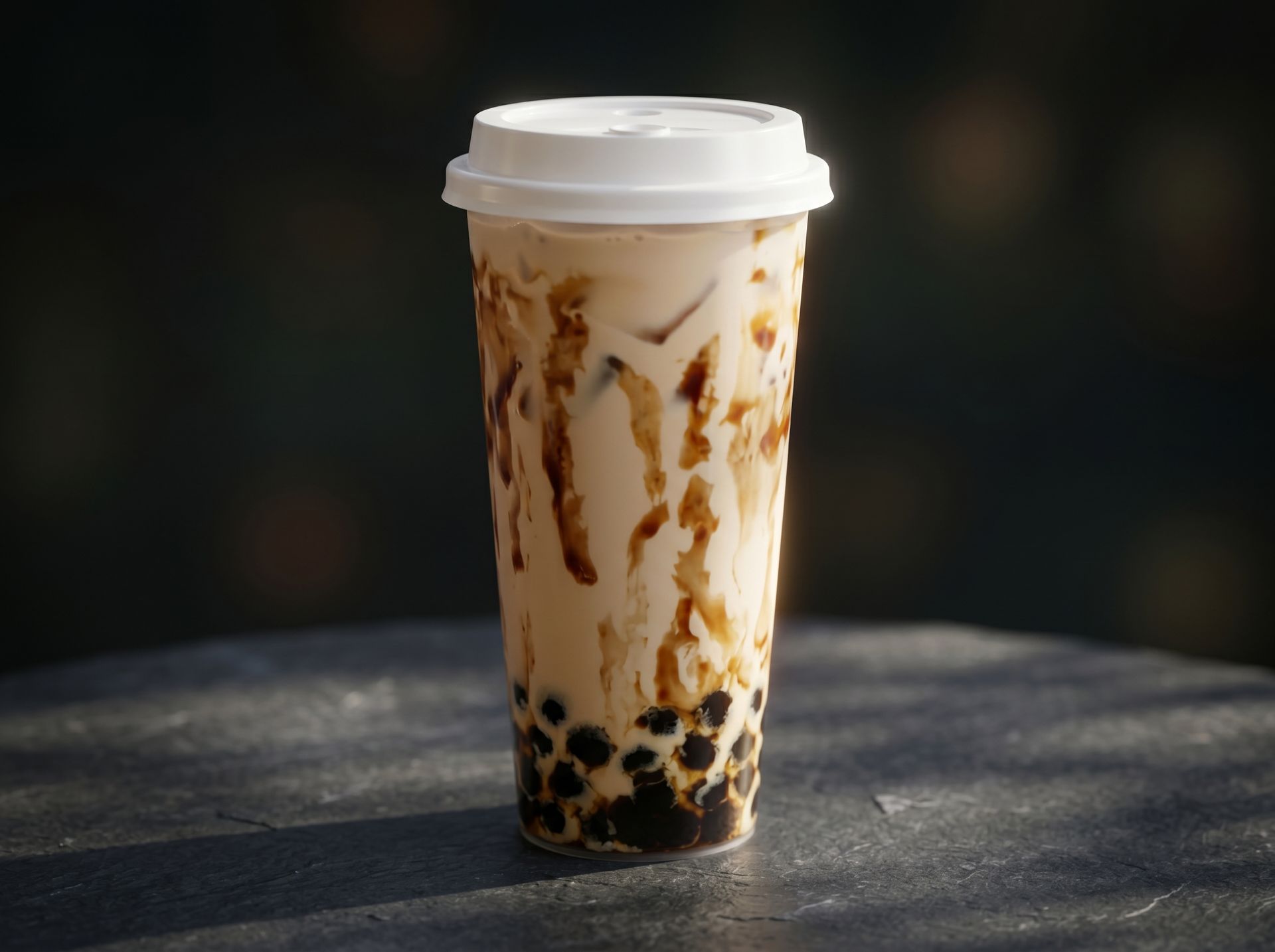 Tall iced bubble tea in a clear cup with milk swirls, black tapioca pearls, and a white lid.