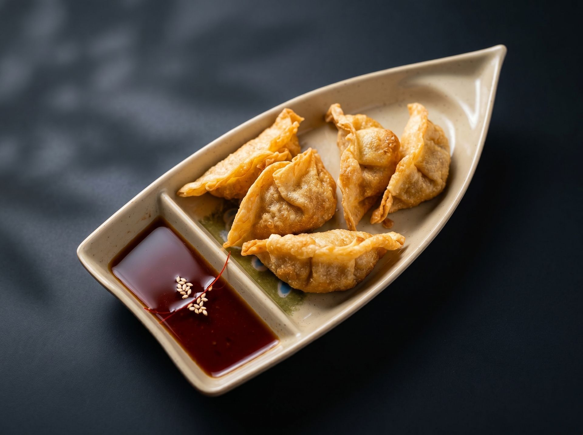 Creamy dipping sauce beside golden fried dumplings on a beige boat-shaped plate