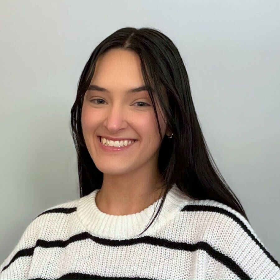Woman with long dark hair smiles wearing a black and white striped sweater.
