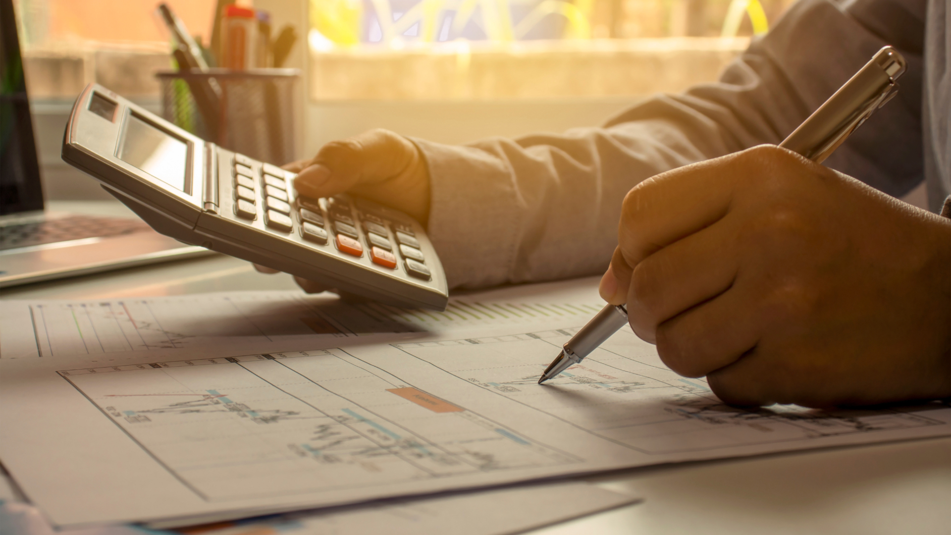 A person is using a calculator and writing on a piece of paper.
