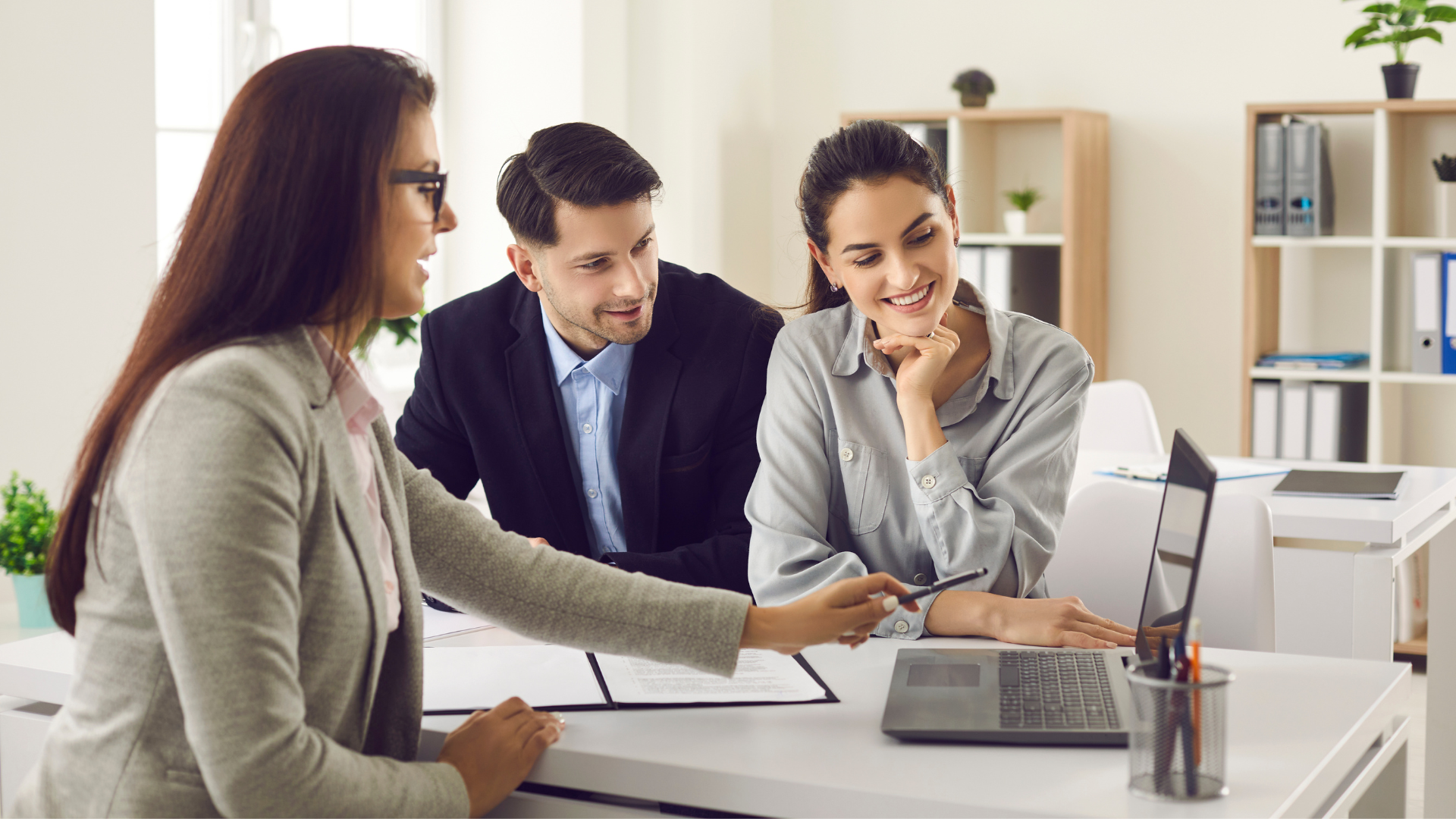 A woman is talking to a man and a woman in an office.