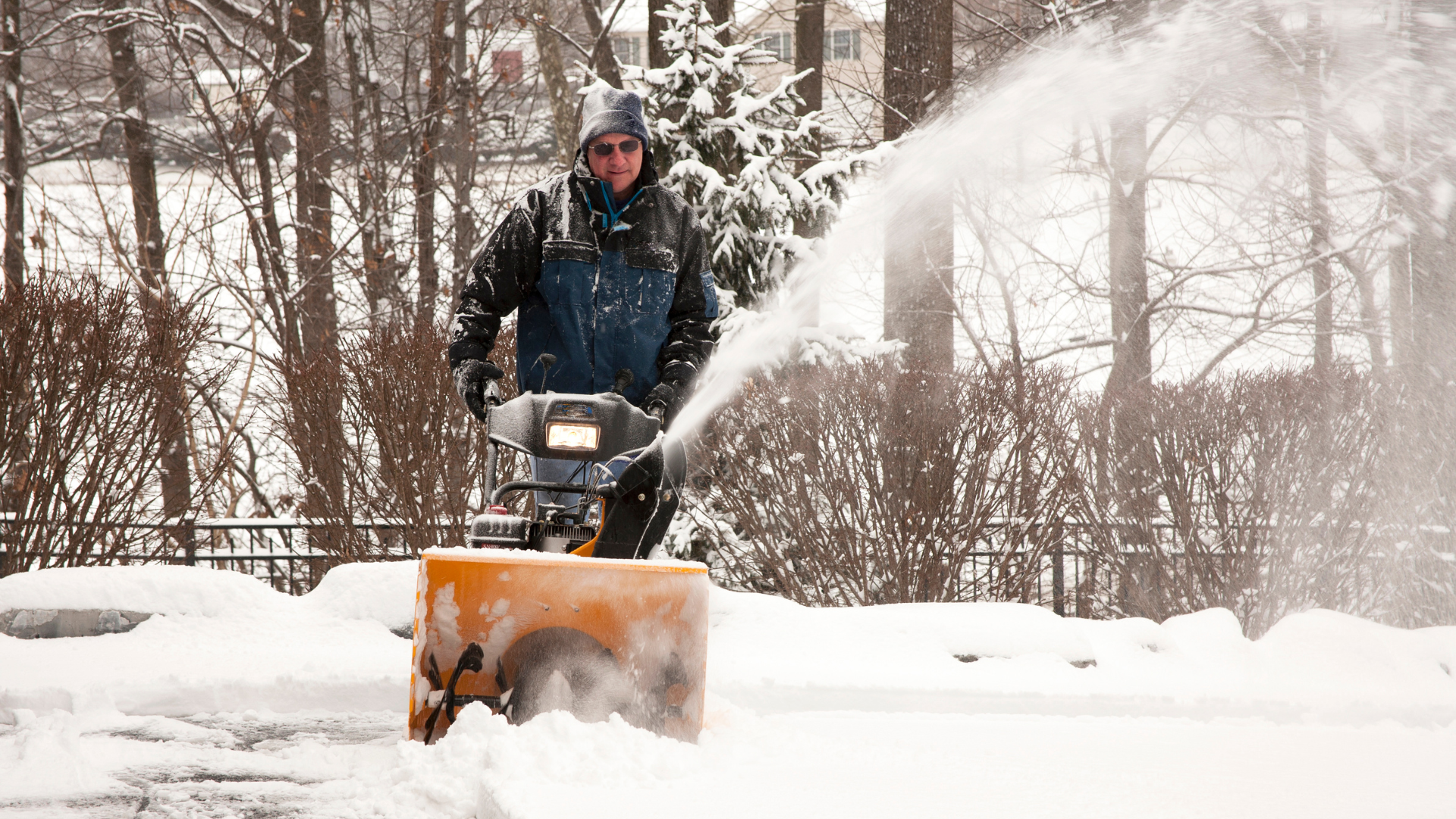 A man is using a snow blower to clear snow from a driveway.
