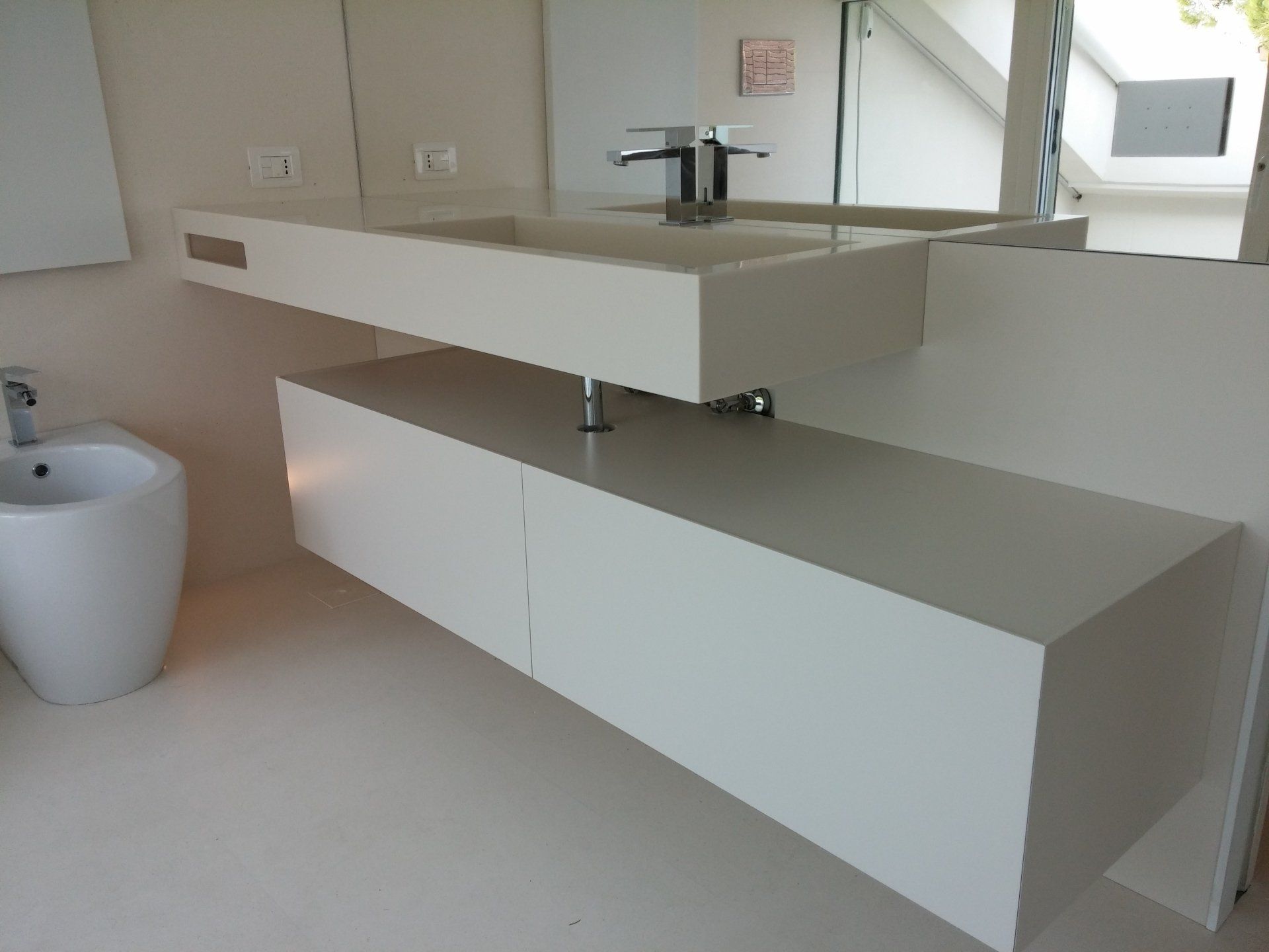 Bagno moderno con mobile lavabo sospeso bianco, doppio lavabo, specchio e armadietti a muro.