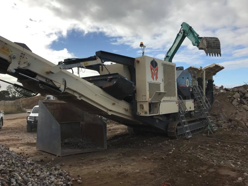 A large machine is sitting on top of a pile of rocks.