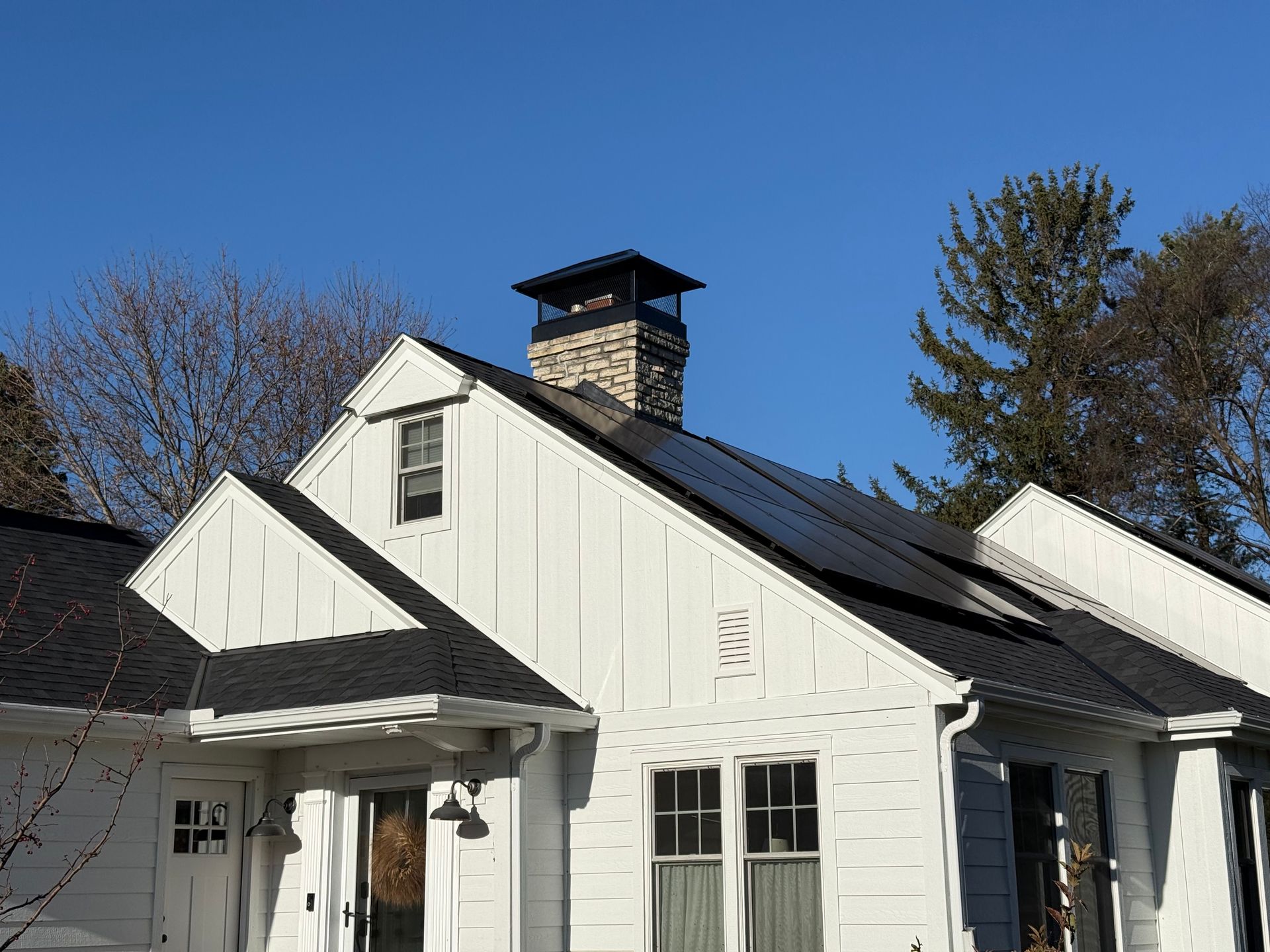 White house with black roof and chimney under a clear blue sky