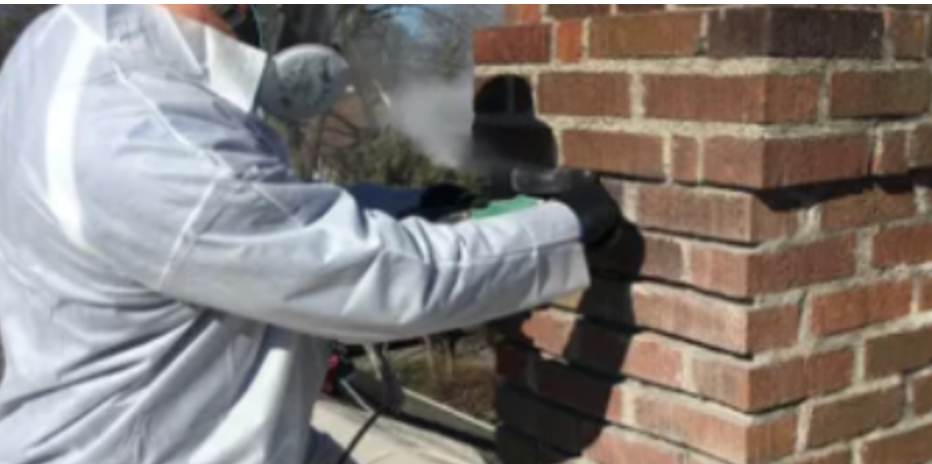 A man is cleaning a brick chimney with a machine.