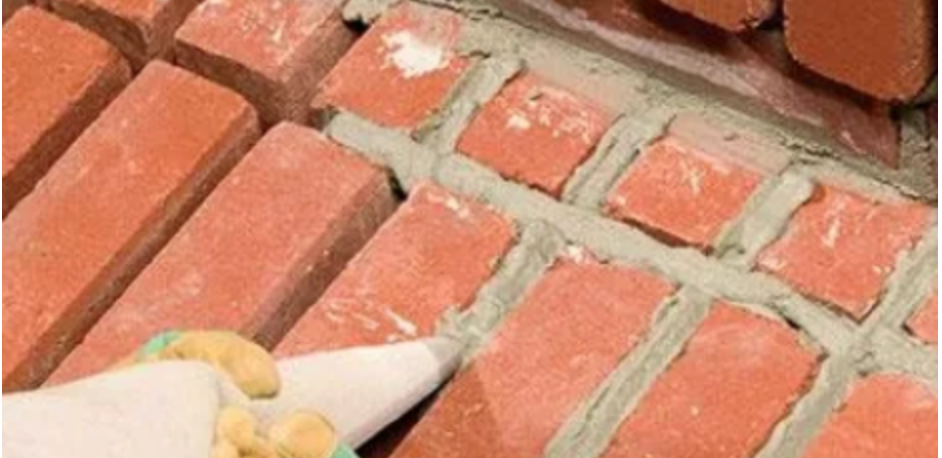 A person is applying mortar to a brick wall.