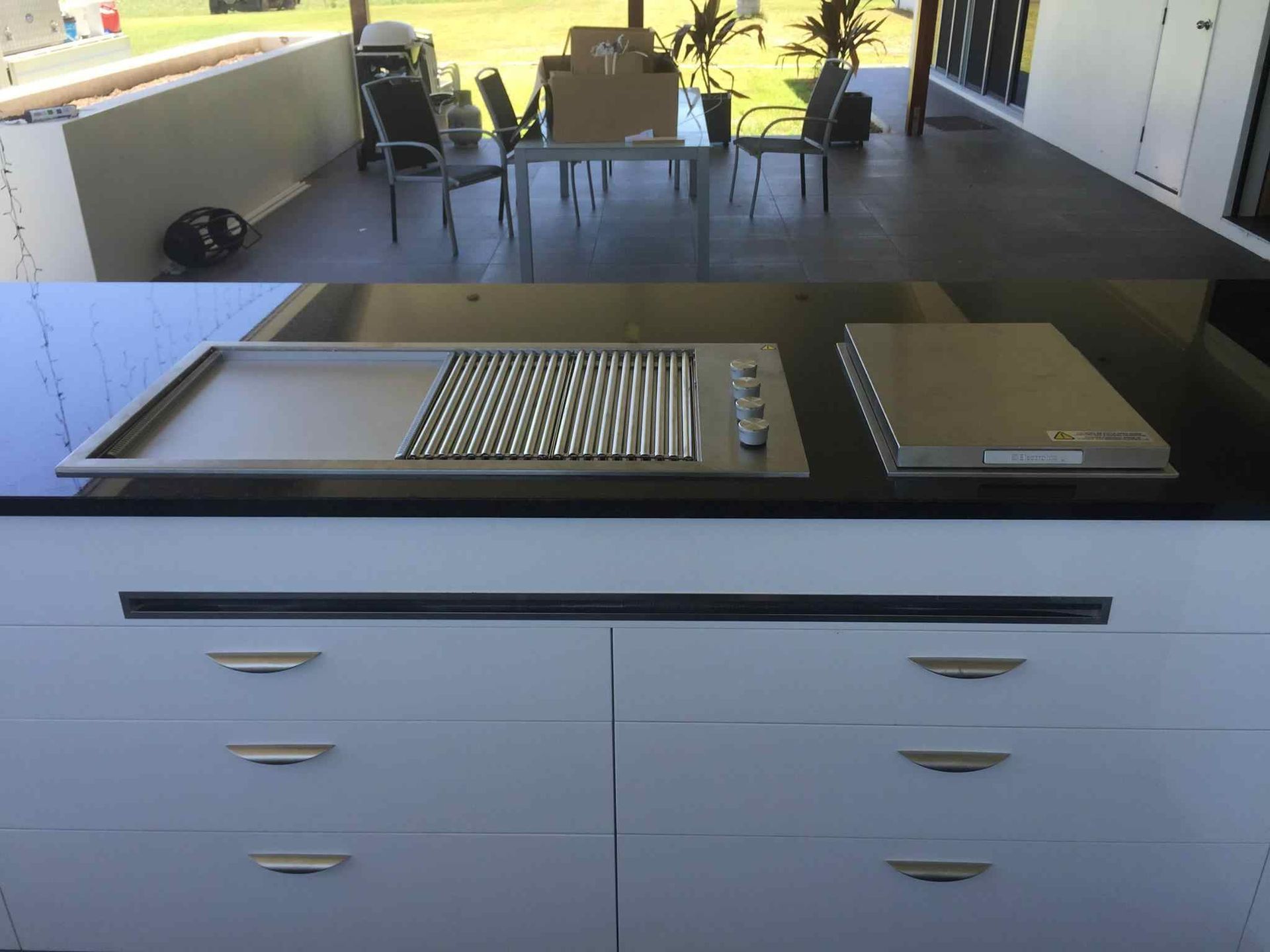 A Kitchen With a Grill and a Table in the Background — Reed Plumbing Industries in Mackay, QLD
