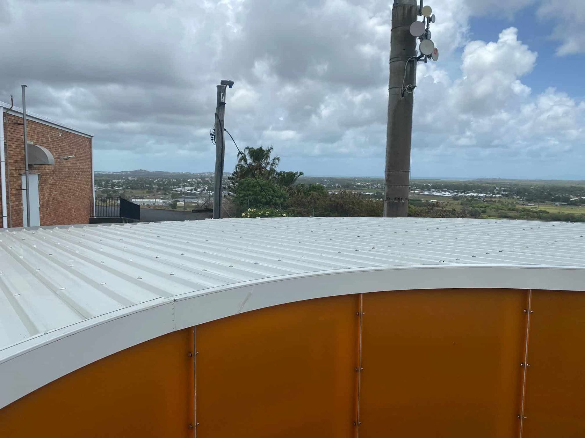A White Roof With a View of a City and a Palm Tree — Reed Plumbing Industries in Paget, QLD