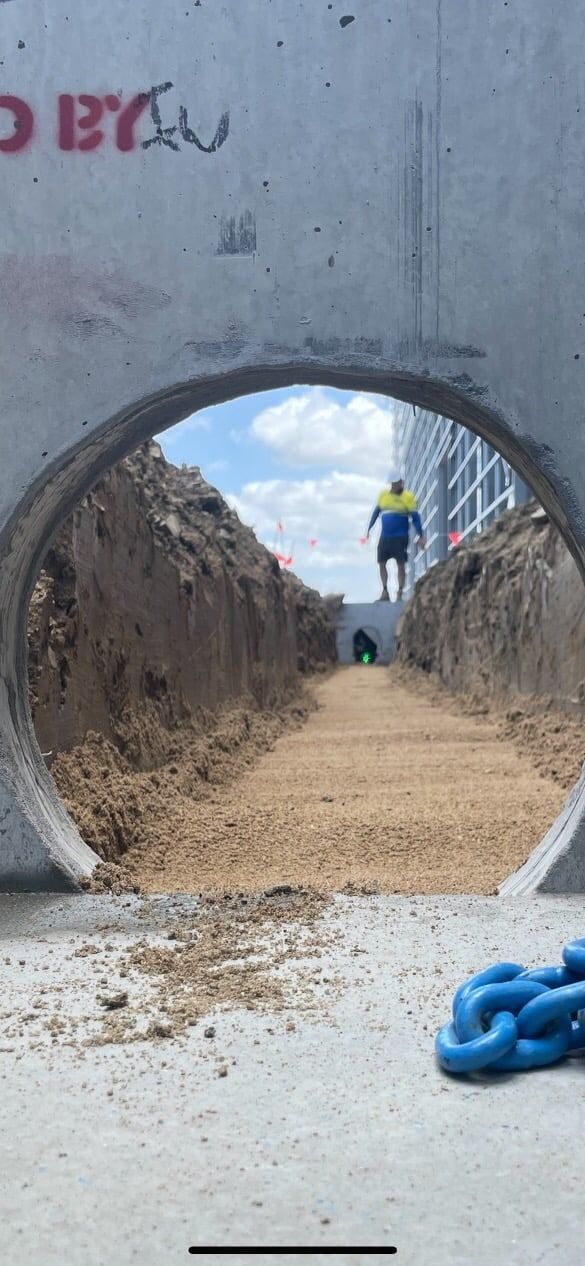 A Man is Walking Through a Hole in the Ground — Reed Plumbing Industries in Mackay, QLD