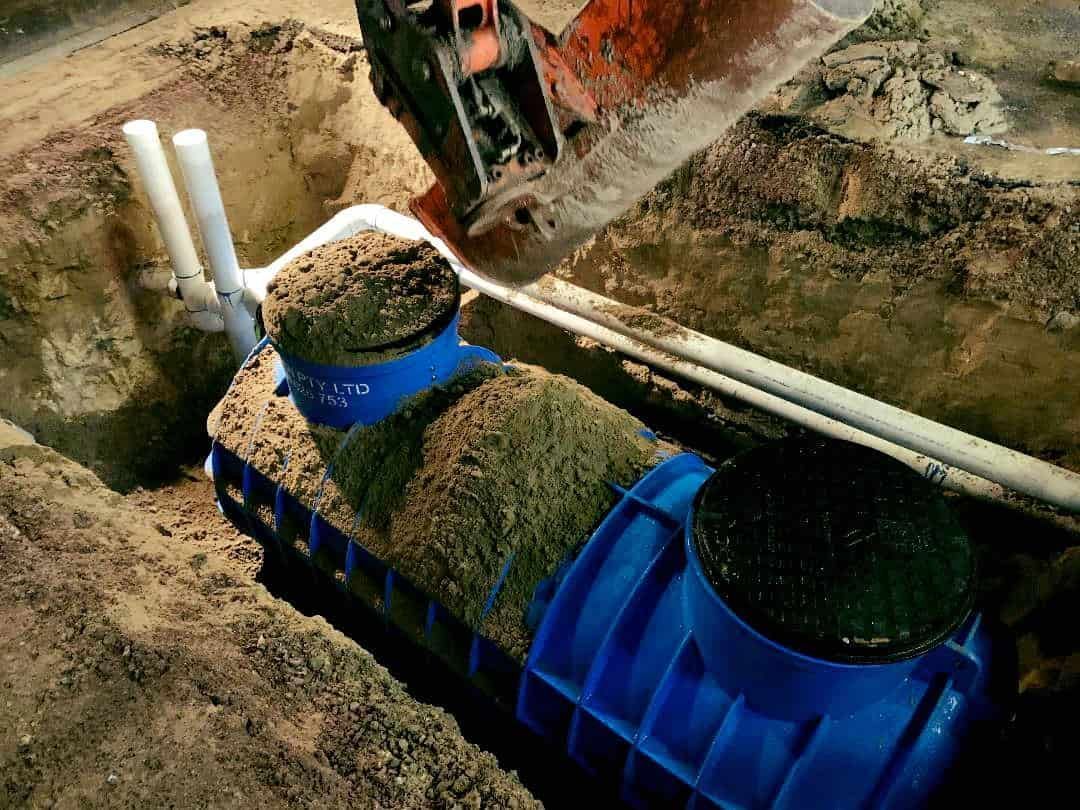 A Blue Septic Tank is Being Installed in a Hole in the Ground — Reed Plumbing Industries in Andergrove, QLD