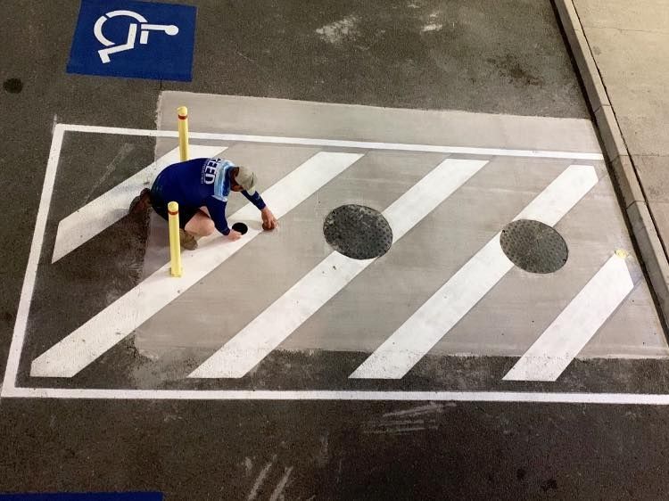 A Person is Painting a Handicapped Parking Spot on the Ground — Reed Plumbing Industries in Mackay, QLD