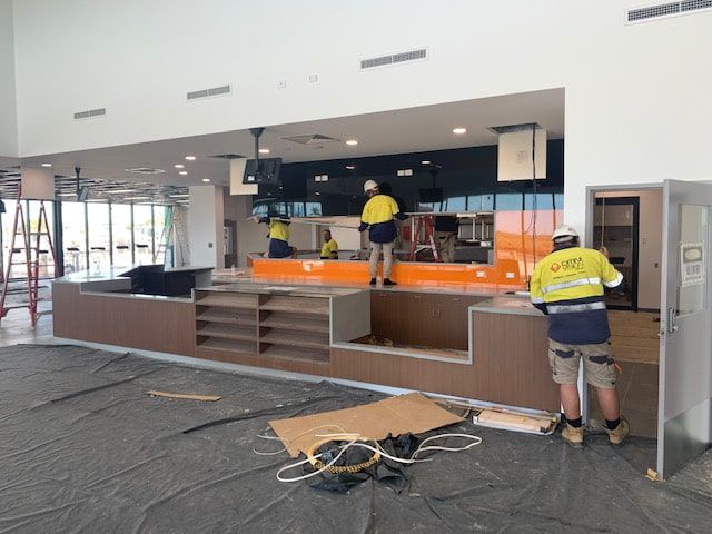 A Group of Construction Workers Are Working on a Building — Reed Plumbing Industries in Paget, QLD