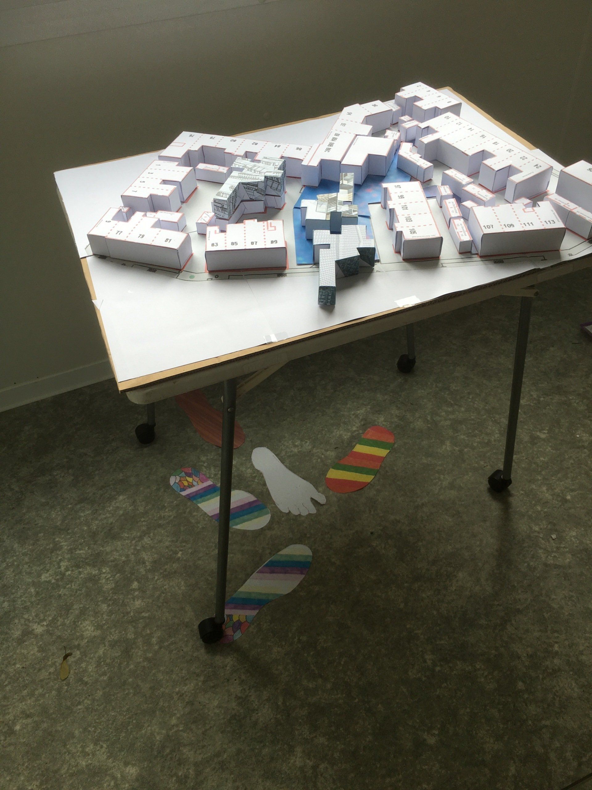 Een architectonisch tafelmodel, gemaakt van witte en blauwe blokken, staat op een witte tafel in een kamer.