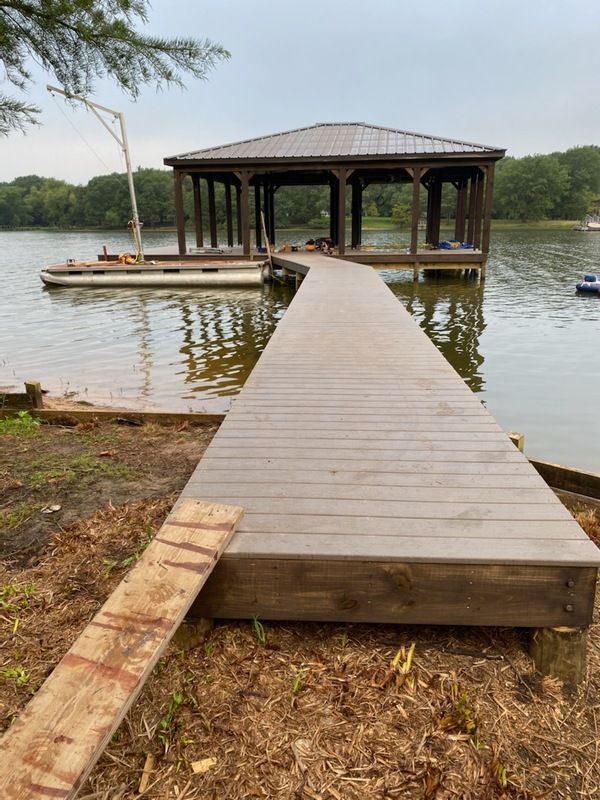 A wooden dock leading to a boathouse on a lake.