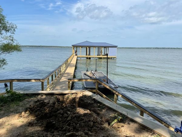 A dock with a boat docked at the end of it on a lake.