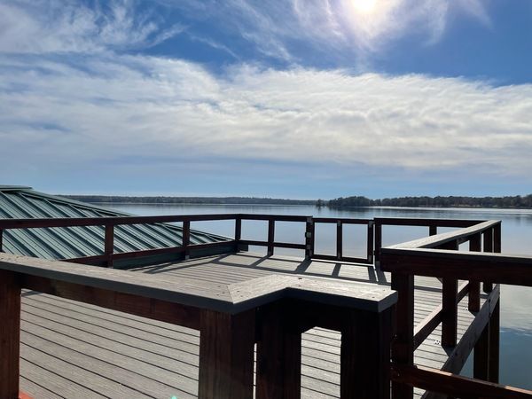 A wooden deck overlooking a lake on a sunny day