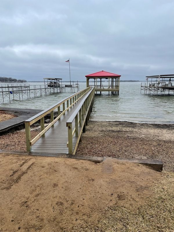 A wooden dock leading to a gazebo on a lake.