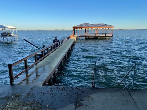 A man is sitting on a dock in the middle of a lake.