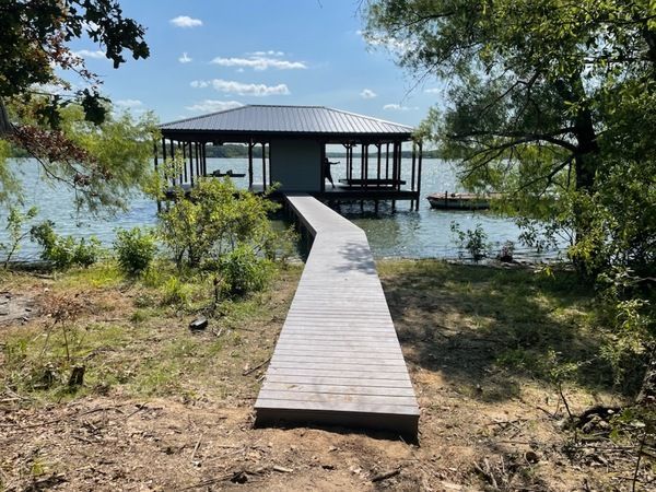 A wooden walkway leading to a dock on a lake.
