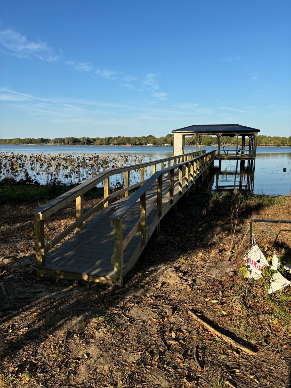 A wooden bridge over a body of water with a gazebo in the background.