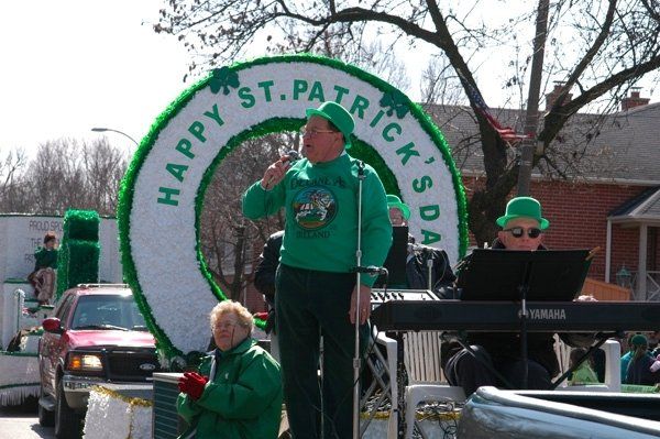 A man stands in front of a sign that says happy st. patrick 's day