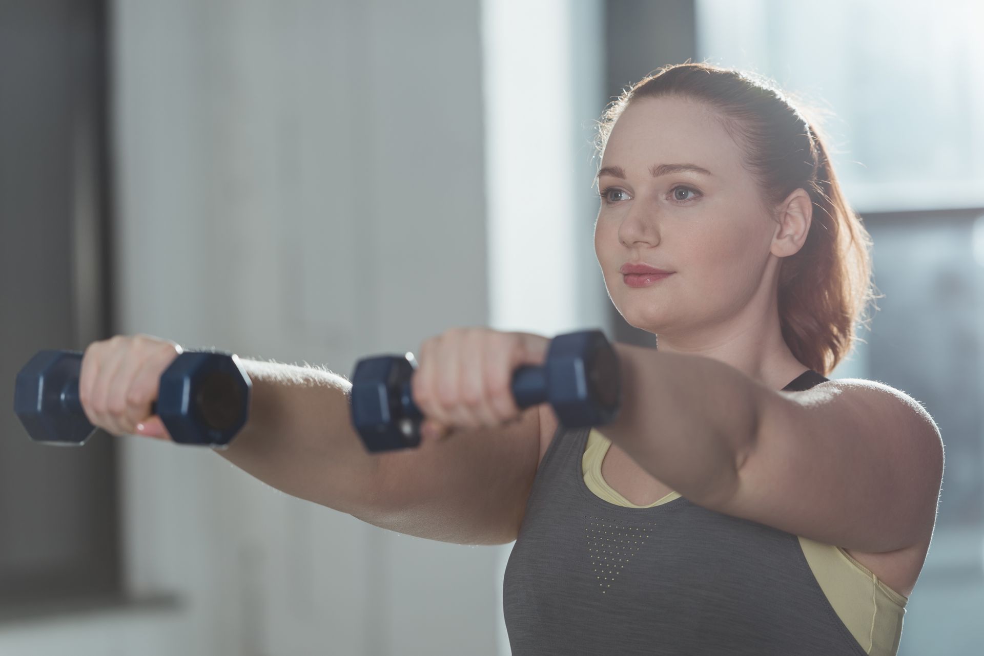 Girl training with dumbbells at a gym.