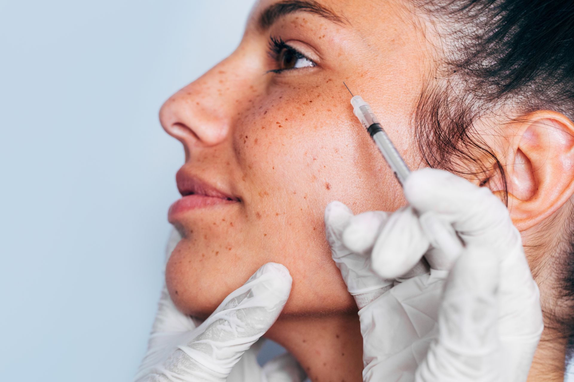 Close-up of a gloved provider injecting Botox into a woman's cheek during a Jacksonville FL treatment.