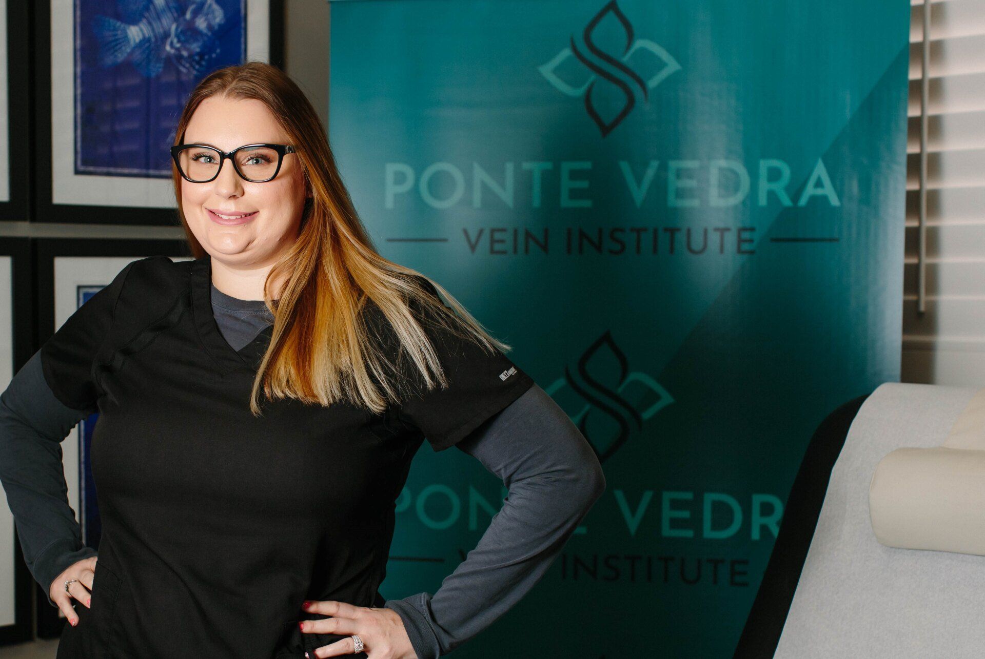 Woman in scrubs stands in front of aPonte Vedra Vein & Aesthetics sign.