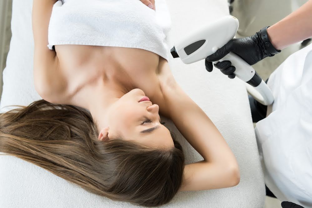 Woman receiving underarm laser hair removal treatment.