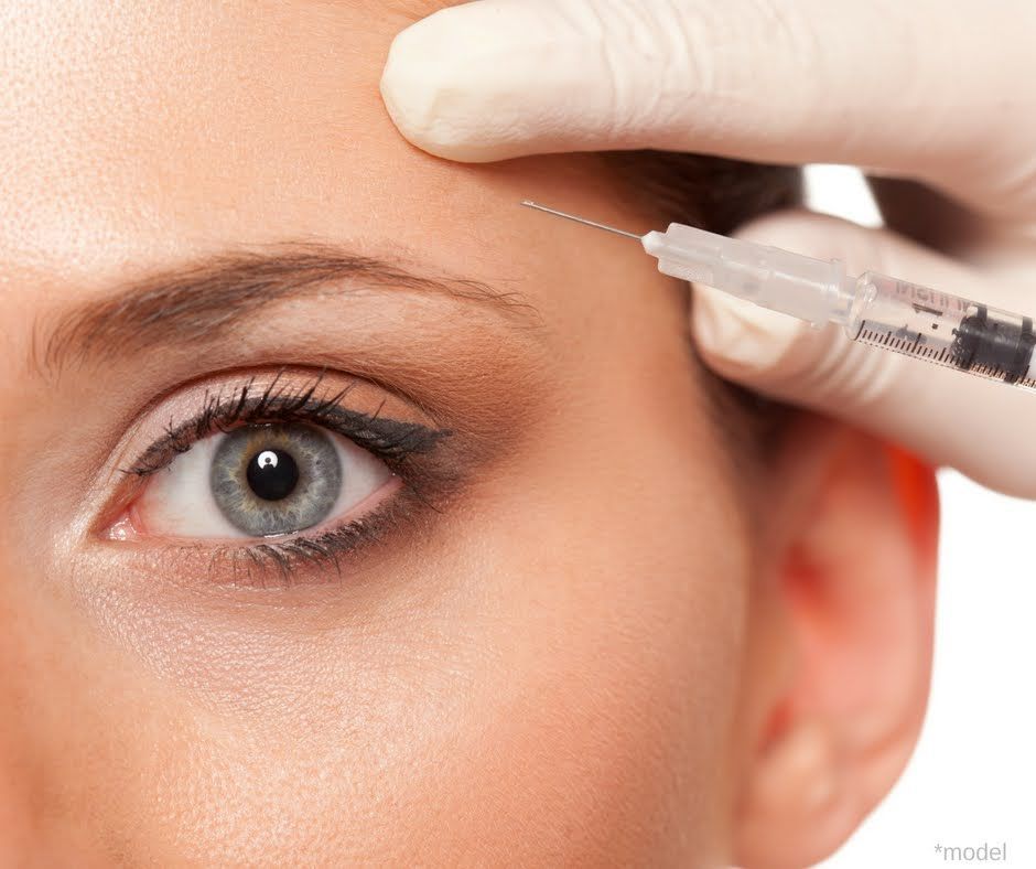 Close-up of a person's eye and brow as they receive a cosmetic injection to the forehead.