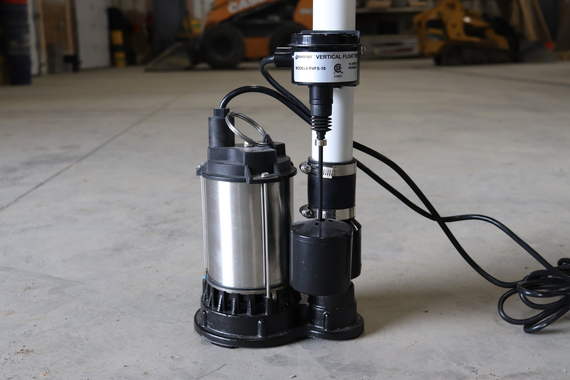 Sump pump with float switch, electrical cord, mounted on concrete floor, interior.