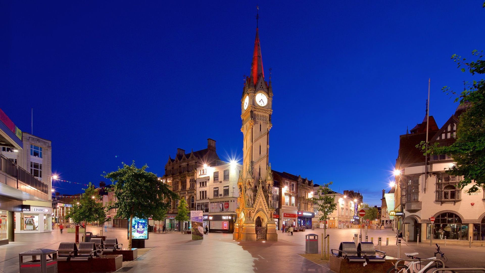 A clock tower in the middle of a city at night