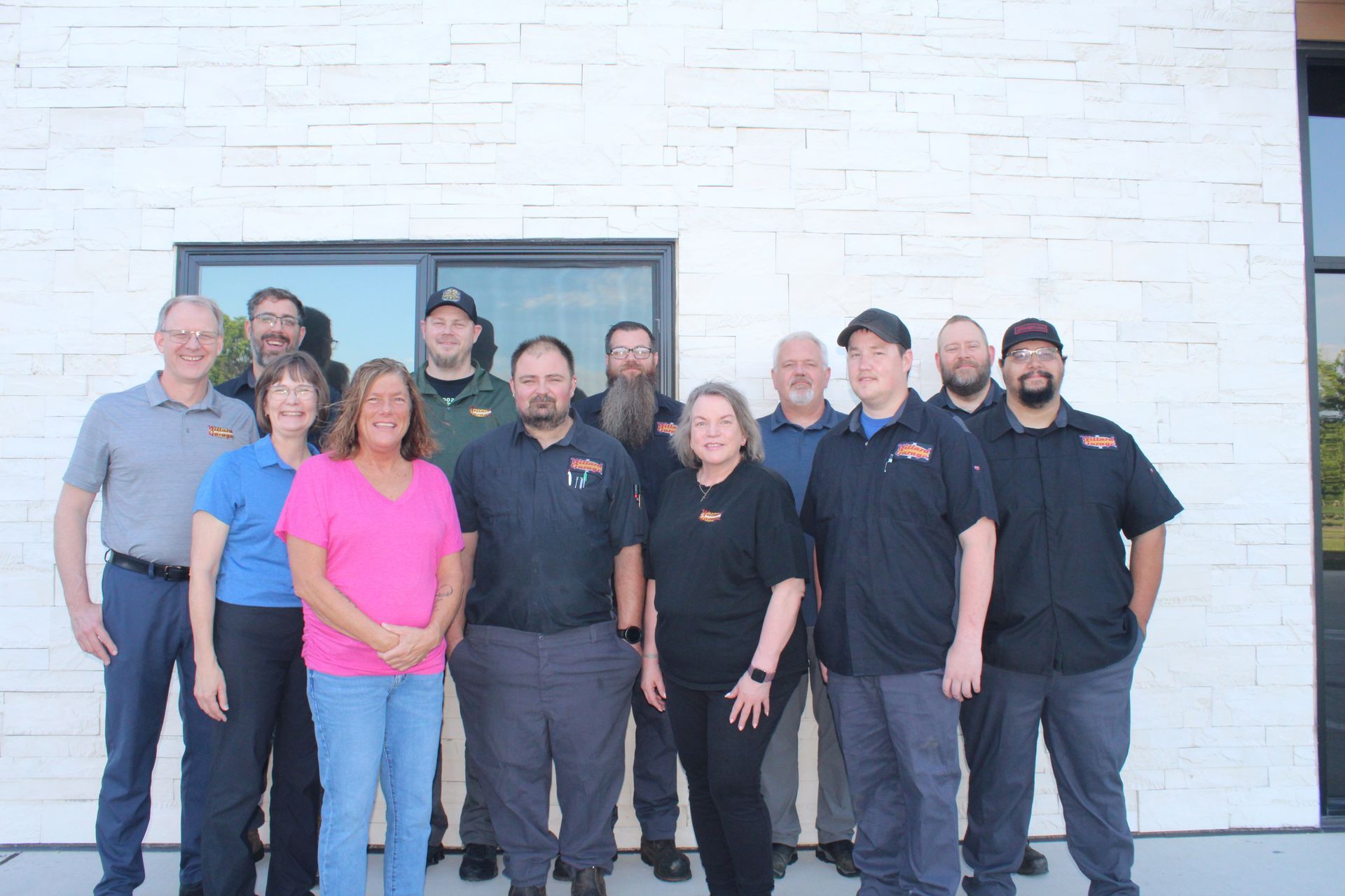 Group of staff standing outside a building, most in dark shirts, with one woman in a bright pink top.