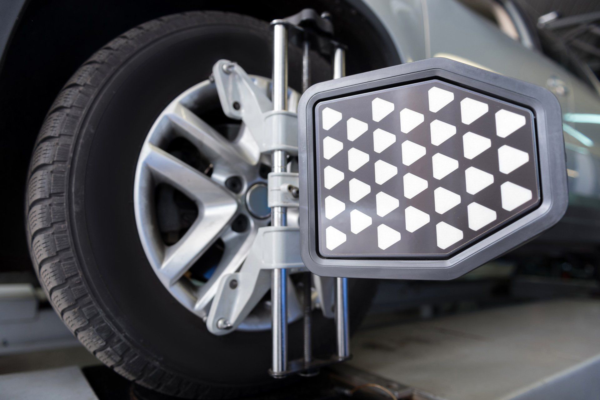 Wheel alignment machine measuring a car tire with a triangular sensor panel attached