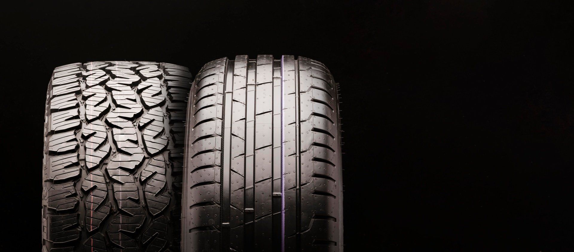 Two black tires side by side, showing a rugged tread and a smooth tread pattern.