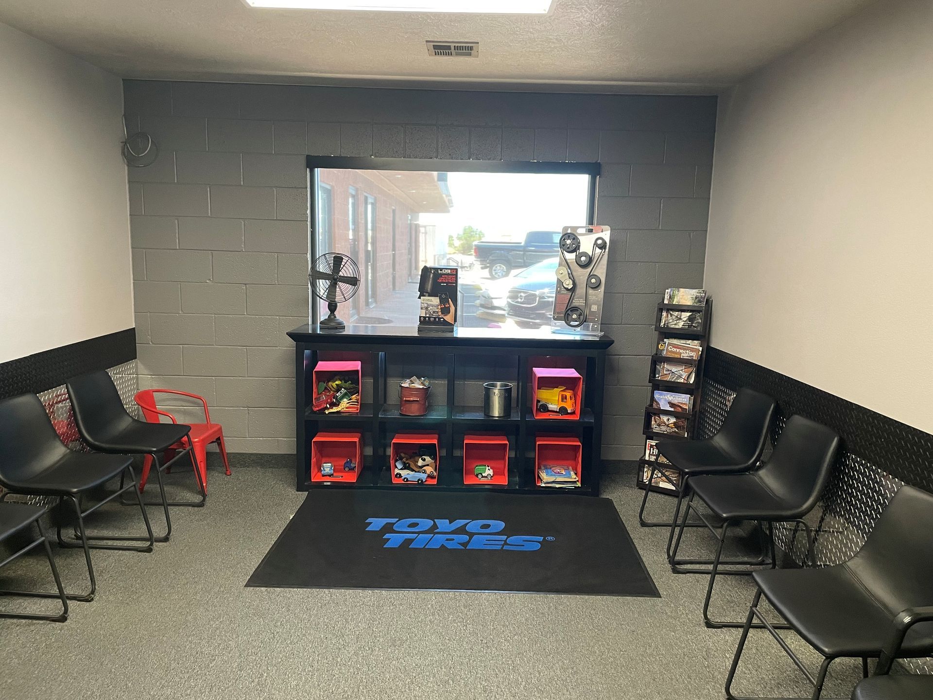 Small lobby with black chairs, a shelf of snacks, and a large front window.