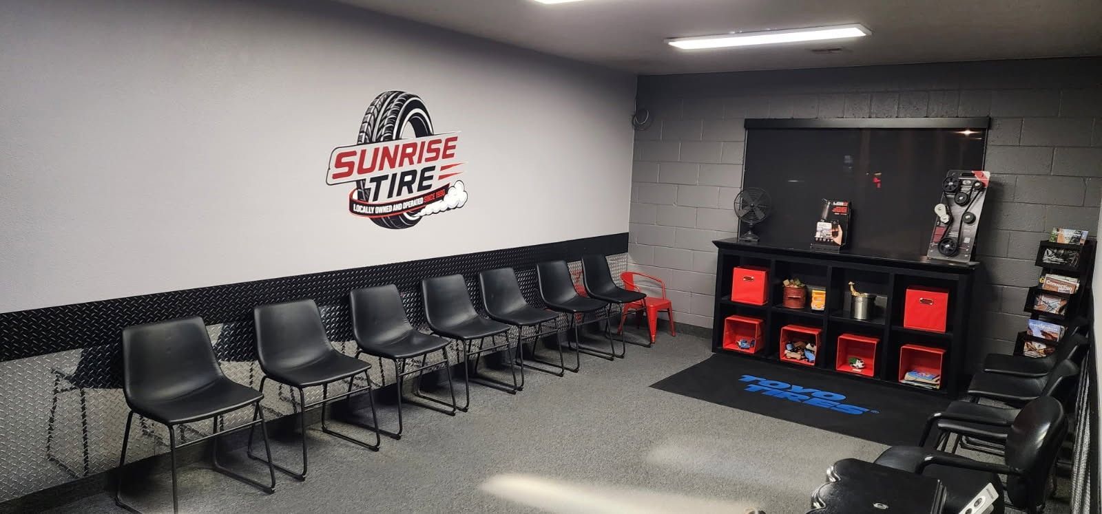 Team waiting room with black chairs, wall logo, and a shelving display of trophies and memorabilia