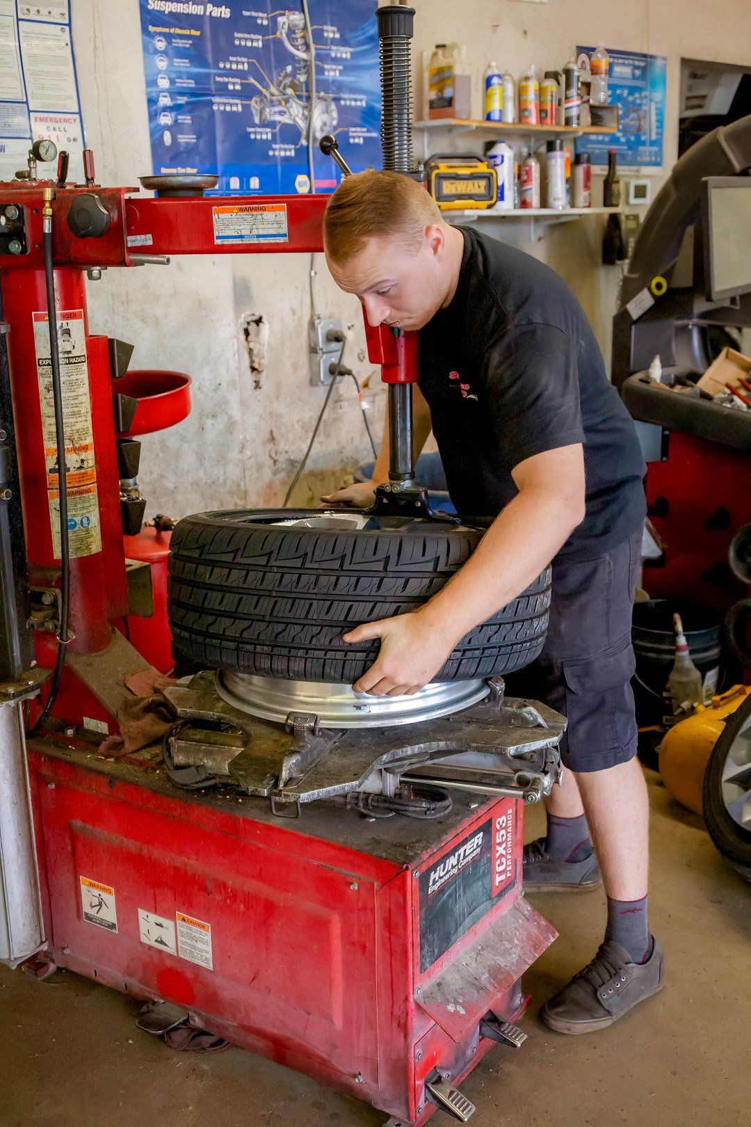 Mechanic changing a tire on a red tire machine in an auto repair shop