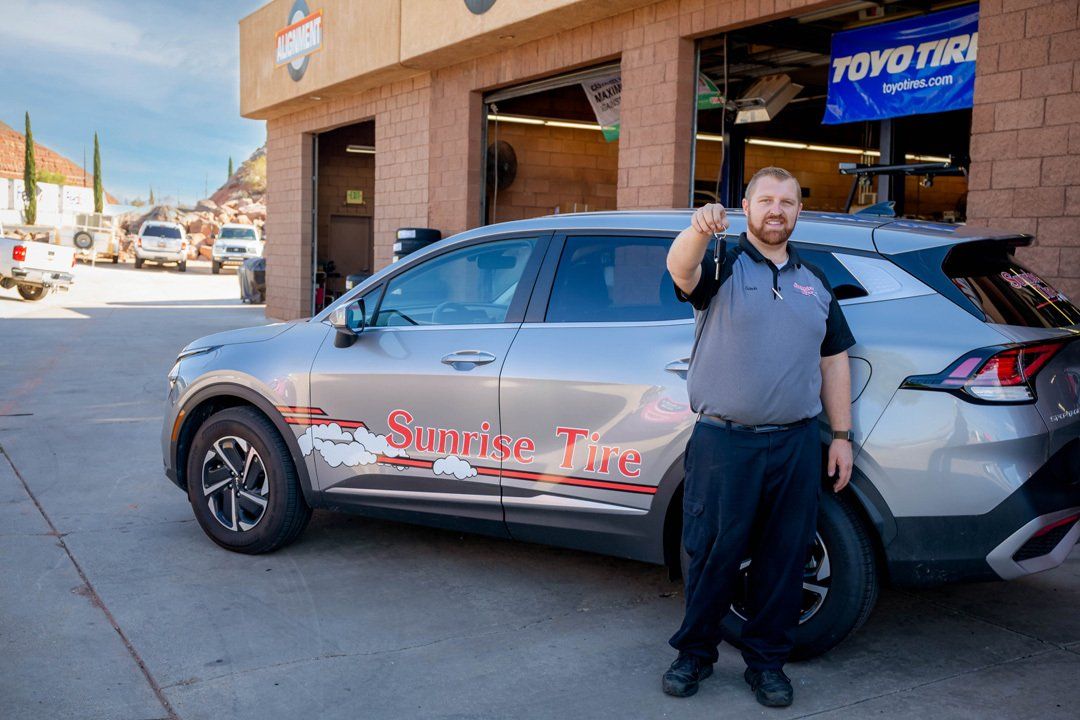 Man standing beside a silver SUV with a red logo outside a Toyota dealership