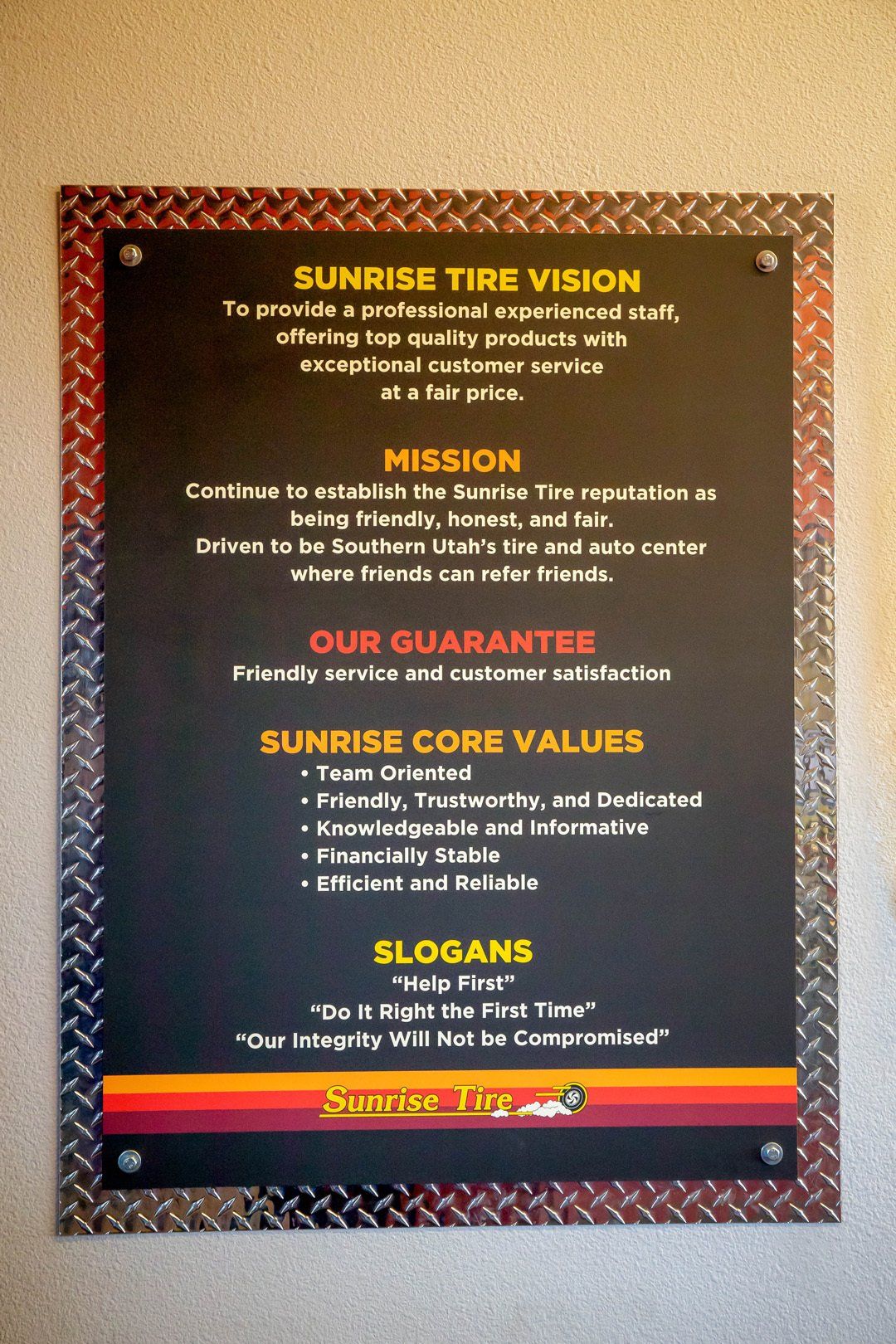 Sunrise Tire Vision poster with mission, values, and slogans on a brown wall