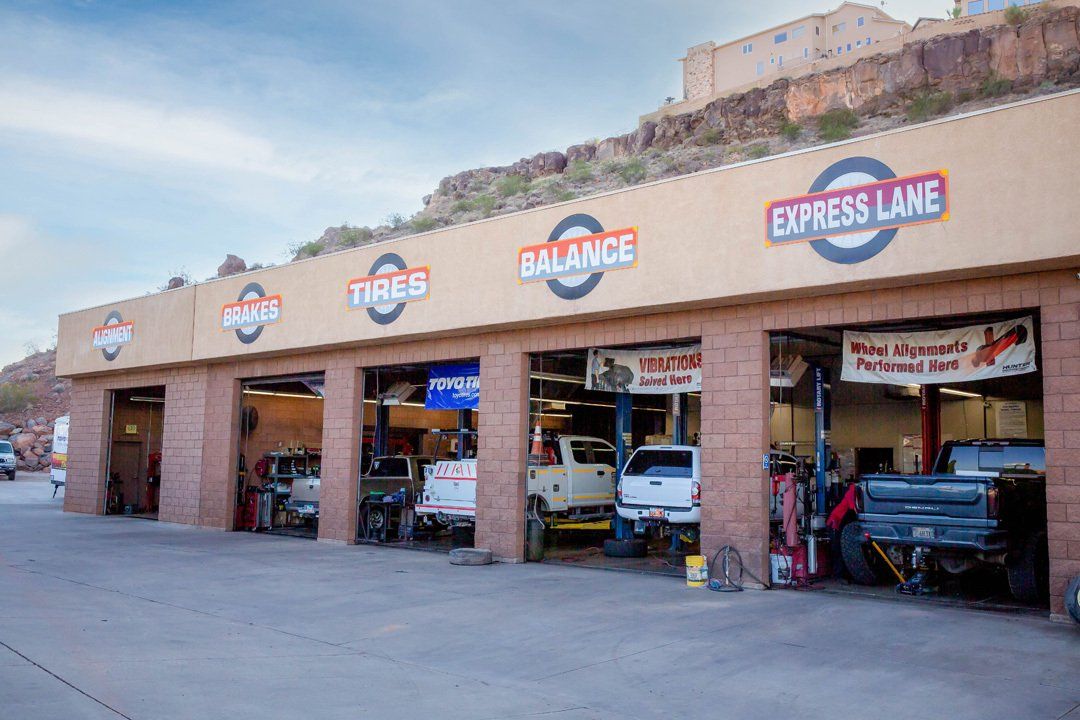Auto repair shop with open service bays and vintage gas station signs under a desert hillside