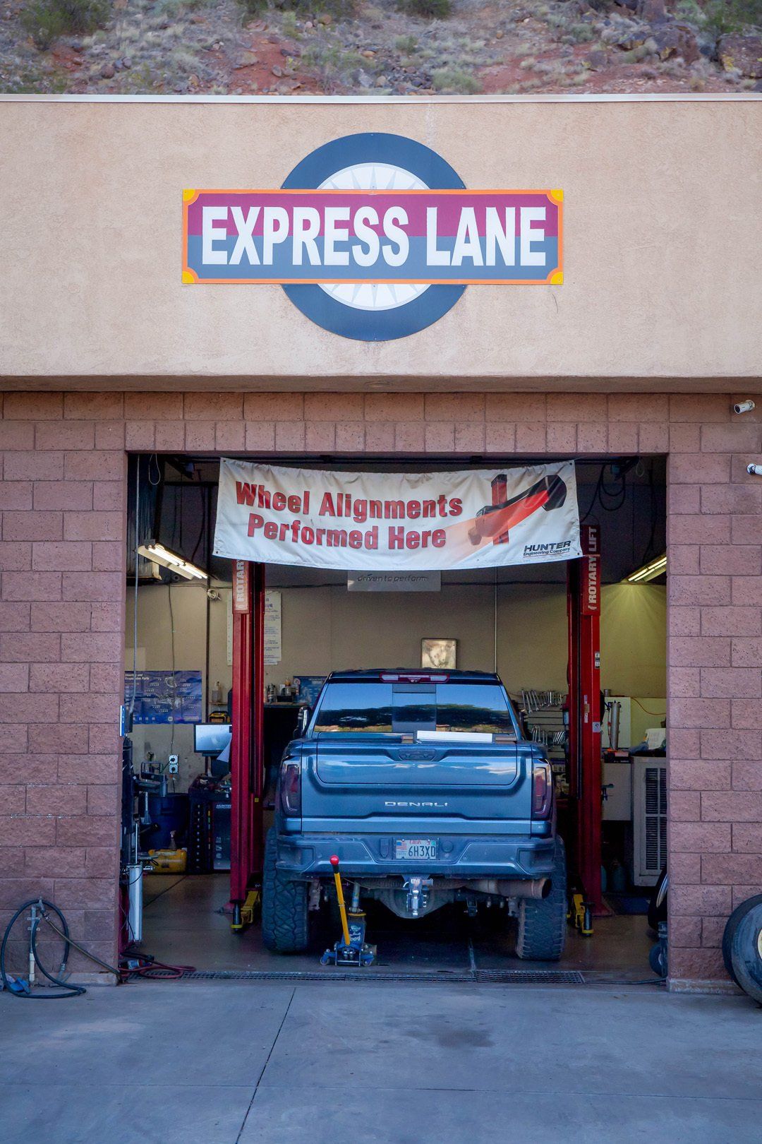 Blue pickup truck inside an auto repair bay beneath an “Express Lane” sign.