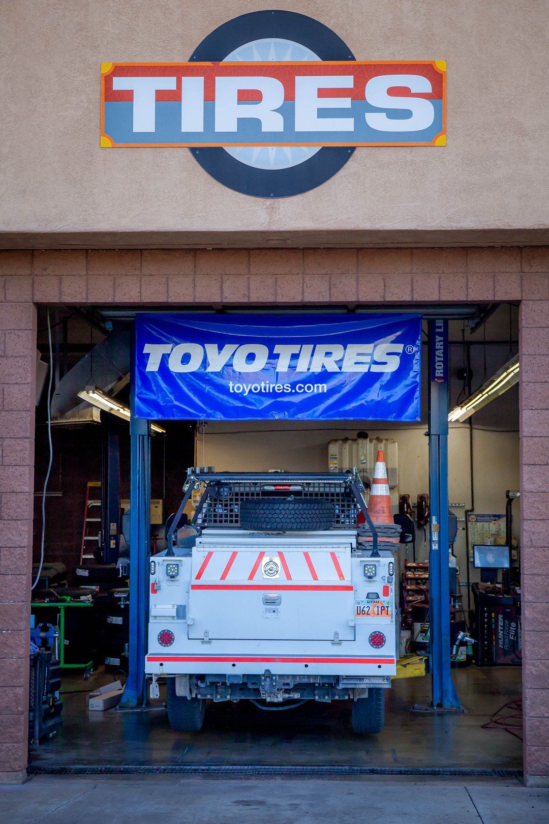 Auto tire shop entrance with a lifted white off-road vehicle under a TOYO TIRES banner